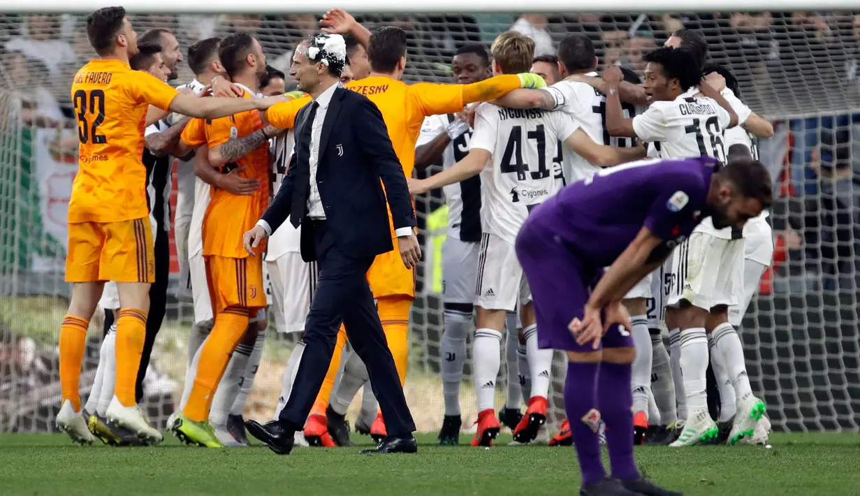 Pemain Fiorentina tertunduk ketika para pemain Juventus merayakan kemenangan mereka dalam Serie A Liga Italia di Stadion Allianz, Turin, Italia, Sabtu (20/4). Juventus menjuarai Serie A Liga Italia 2018/2019. (AP Photo/Luca Bruno)