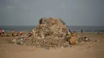Petugas kebersihan berada di samping tumpukan sampah plastik terlihat di pantai Juhu di Mumbai, India (2/6). (AFP PHoto/Punit Paranjpe)