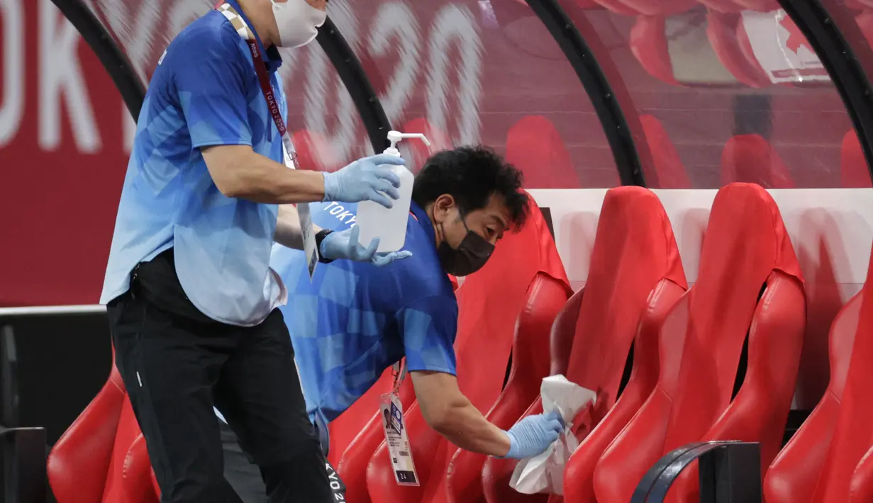 Petugas mendisinfeksi kursi untuk menghentikan penyebaran virus corona COVID-19 setelah pertandingan sepak bola putaran pertama grup C putra Olimpiade Tokyo 2020 antara Mesir dan Spanyol di Sapporo Dome, Sapporo, Jepang, Kamis (22/7/2021). (ASANO IKKO/AFP)