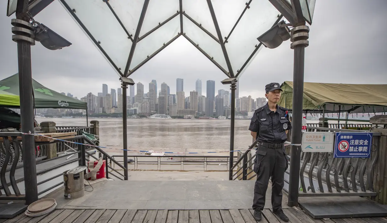 Seorang petugas berjaga di dekat tepi Sungai Yangtze di Kota Chongqing, China barat daya (18/8/2020). Kota Chongqing dilanda banjir parah. Status tanggap darurat Level I dikeluarkan pada Selasa (18/8) untuk pengendalian banjir. (Xinhua/Huang Wei)