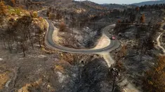 Pemandangan udara ini menunjukkan sebuah jalan yang membentang di sepanjang lahan yang terbakar akibat kebakaran hutan di dekat desa Jonquieres, di departemen Aude, Prancis Selatan, pada 18 Agustus 2025. (Lionel BONAVENTURE/AFP)