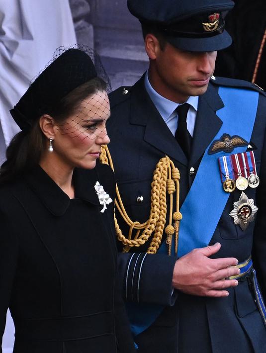 Kate Middleton bersama Pangeran William berjalan mengikuti prosesi persemayaman Ratu Elizabeth II di Westminster Hall di London (14/9/2022). Bros yang dikenakan Kate ini dulu dimiliki oleh Ratu Elizabeth II, sebelum diberikan kepada istri Pangeran William tersebut.  Dalam situs The Court Jeweller, sang ratu pernah menggunakan bros tersebut dalam kunjungan ke Seoul, Korea Selatan pada 1999. (AFP/Ben Stansall)