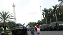 Warga berpose berlatar Tugu Monas dan kendaraan taktis TNI di kawasan Monumen Nasional, Jakarta, Jumat (19/4). Libur panjang perayaan Paskah 2019 dimanfaatkan warga untuk berwisata di kawasan Monumen Nasional. (Liputan6.com/Helmi Fithriansyah)
