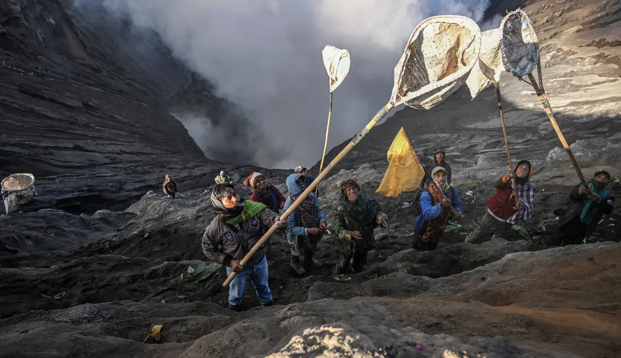 <p>Warga menggunakan jaring untuk menangkap sesajen yang dilemparkan oleh masyarakat Suku Tengger di kawah gunung Gunung Bromo sebagai bagian dari festival Yadnya Kasada di Probolinggo, Jawa Timur, Senin (5/6/2023). (Photo by Juni Kriswanto / AFP)</p>