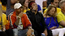 Lewis Hamilton berbincang dengan Neymar Jr saat menyaksikan pertandingan gim kedua Final NBA antara Cleveland Cavaliers melawan Golden State Warriors di Oracle Arena, Oakland, California, AS, (4/6). (Ezra Shaw/Getty Images/AFP)