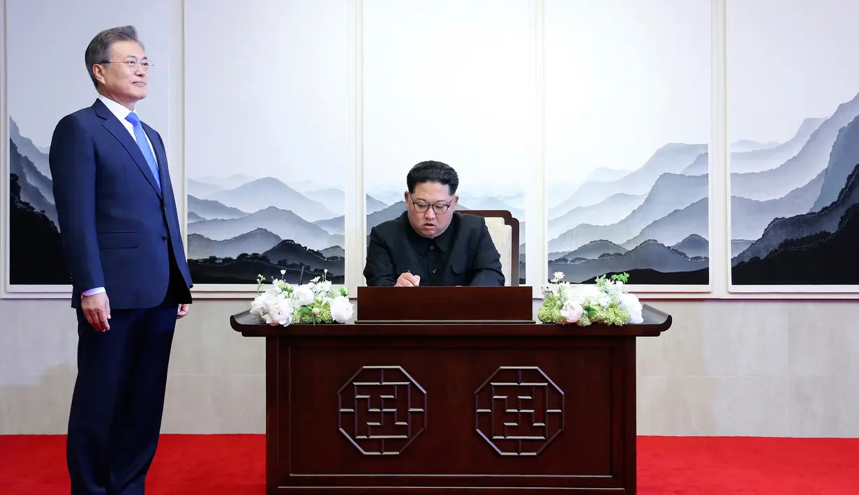 Pemimpin Korea Utara, Kim Jong-un menandatangani buku tamu di Peace House Panmunjom di sebelah Presiden Korea Selatan, Moon Jae-in sebelum melakukan pertemuan antar-Korea, Jumat (2/4). (Korea Summit Press Pool via AP)
