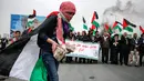 Seorang wanita Palestina membawa batu selama bentrokan dengan tentara Israel dalam demonstrasi untuk memperingati Hari Tanah di Tepi Barat, Sabtu (30/3).(Photo by ABBAS MOMANI/AFP)