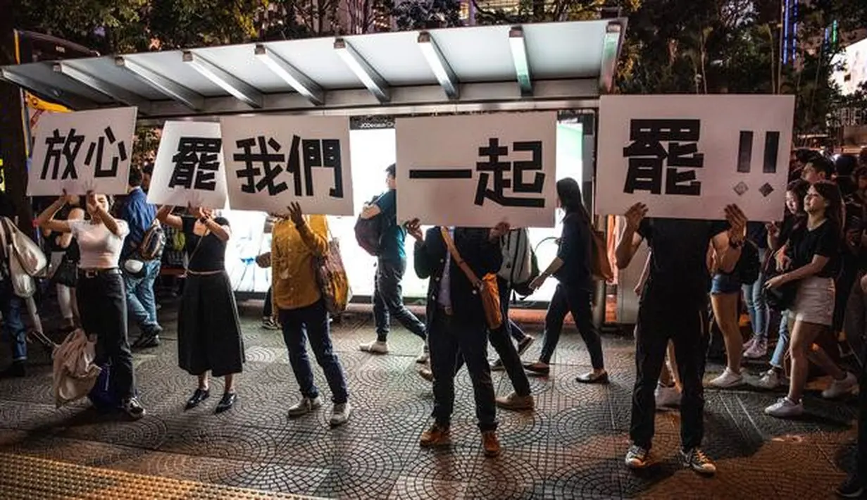 Demonstran menunjukkan pesan tuntutan mereka saat ribuan pegawai negeri sipil (PNS) mengikuti unjuk rasa menolak RUU Ekstradisi di Hong Kong, Jumat (2/8/2019). Banyak PNS yang memakai topeng hitam untuk menyembunyikan identitas mereka. (LAUREL CHOR/AFP)