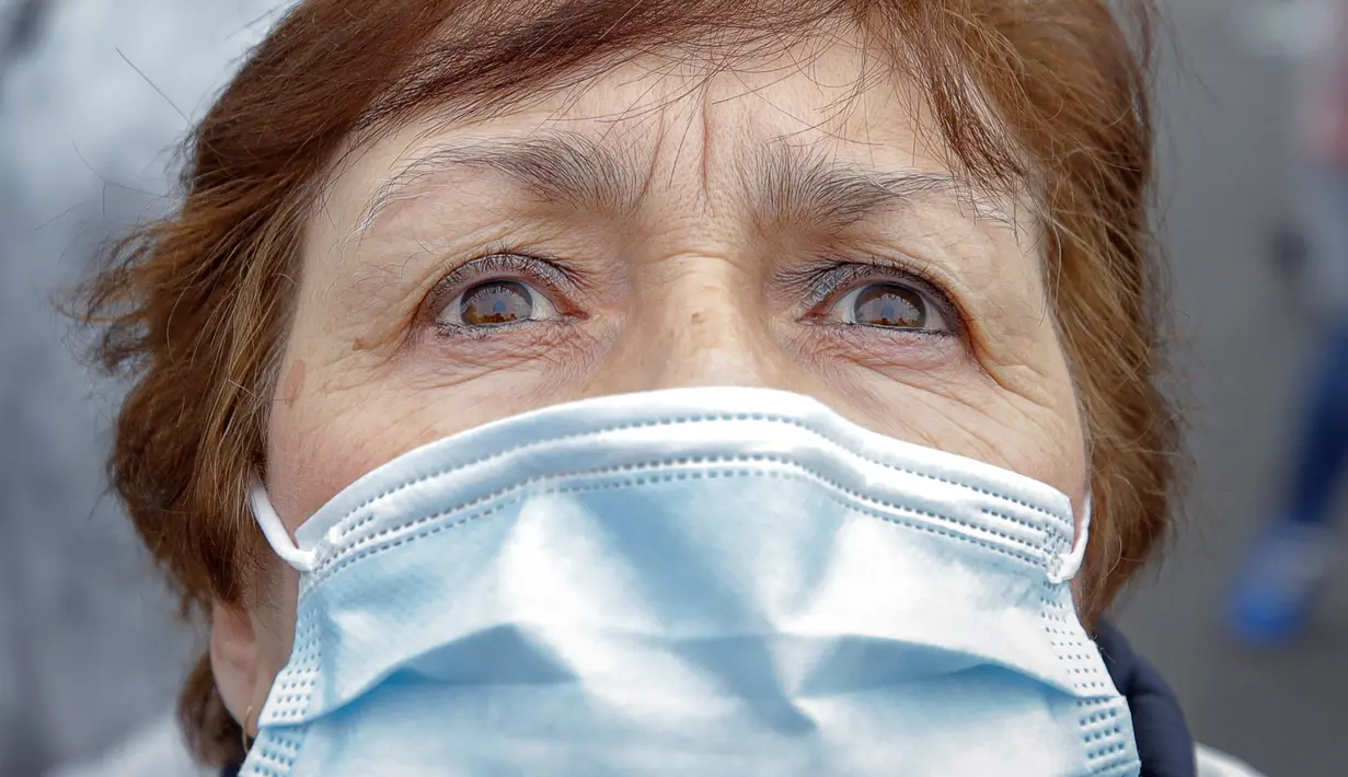Seorang pekerja medis yang mengenakan masker melihat ke atas setelah melepaskan balon hitam di Bucharest, Rumania, Selasa (17/11/2020). Aksi tersebut untuk mengenang pasien COVID-19 yang tewas dalam kebakaran di IGD  sakit di Piatra Neamt, Rumania pada 14 November 2020 lalu.  (AP Photo/Vadim Ghirda)