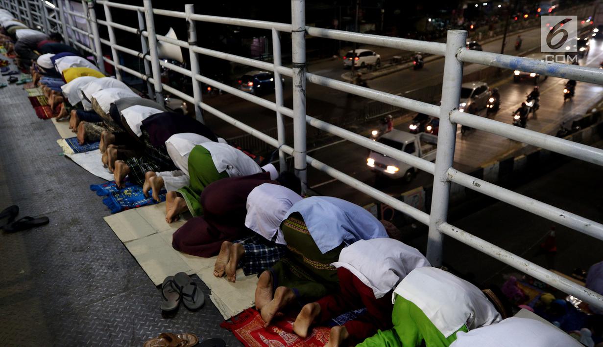 Jemaah melaksanakan salat tarawih di atas JPO akibat melubernya Musala Miftahul Jannah di Kawasan Pasar Gembrong, Jakarta, Kamis (17/5). (Liputan6.com/JohanTallo)