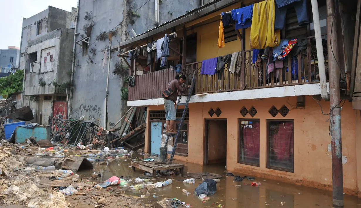 Warga terlihat turun menggunakan tangga dari lantai atas rumahnya menyusul surutnya air yang sempat merendam pemukiman mereka di kawasan Kampung Pulo, Jakarta, Selasa, (17/11). (Liputan6.com/Gempur M Surya)