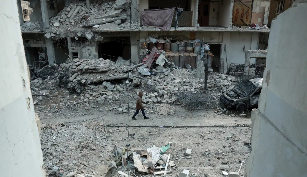 Seorang pria berjalan di antara kehancuran parah akibat  serangan udara rezim pemerintah Suriah di Ghouta Timur, Minggu (25/2). Sekjen PBB António Guterres menggambarkan kondisi di Ghouta timur saat ini sebagai "neraka di bumi". (HAMZA AL-AJWEH/AFP)