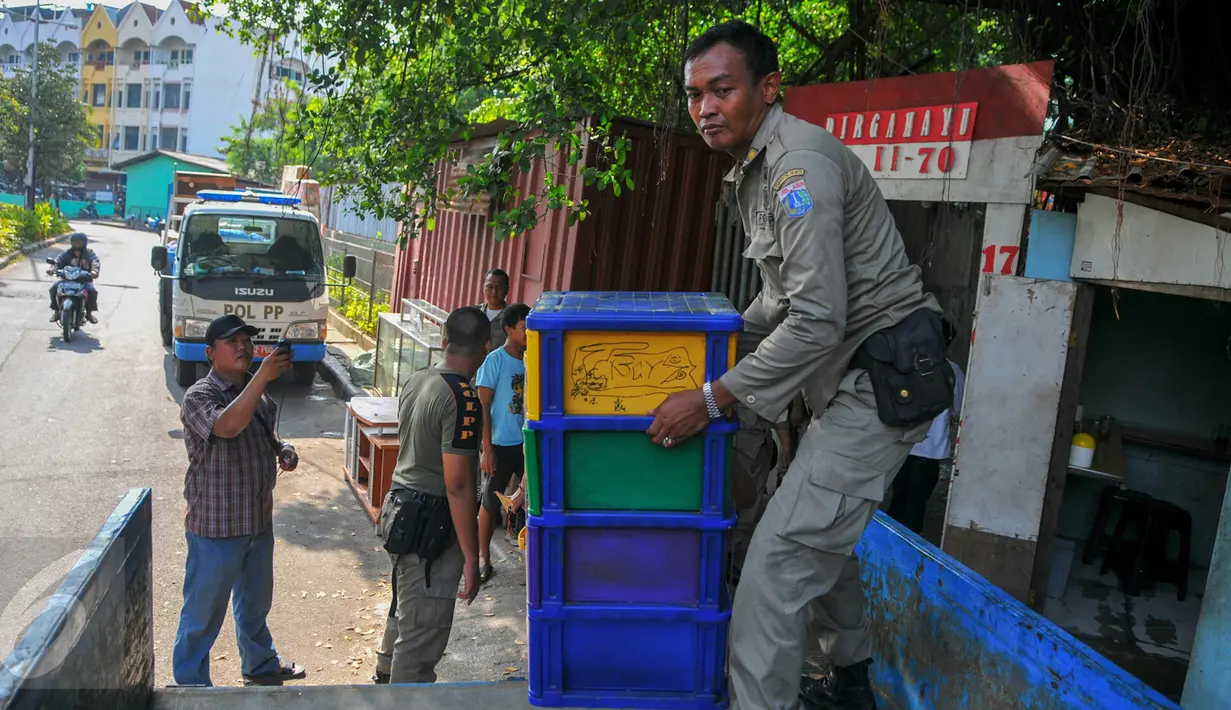 Petugas Satpol PP membantu warga untuk memindahkan barang-barangnya setelah Pemprov DKI memberikan SP2 untuk segera mengosongkan dan meninggalkan rumah mereka di kawasan Pasar Ikan, Penjaringan, Jakarta, Rabu (6/4). (Liputan6.com/Yoppy Renato)