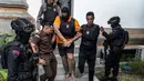 Tiga orang tersangka warga negara Australia yakni Tupou Pasa Midolmore, Coskun Mevlut, dan Darcy Francesco Jenson menjalani proses pelimpahan tahap II (tersangka dan barang bukti) dari penyidik Polres ke pihak Kejaksaan Negeri (Kejari) Badung, Bali pada 15 Oktober 2025. Tampak dalam foto, tersangka Tupou Pasa Midolmore (tengah) saat dibawa kembali ke rumah tahanan setelah menjalani pemeriksaan oleh pihak kejaksaan di Badung, Bali, pada 15 Oktober 2025. (Dicky Bisinglasi/AFP)