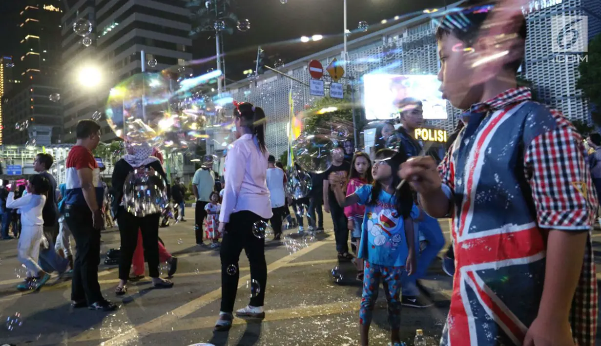 Anak-anak bermain gelembung balon pada malam pergantian tahun di MH Thamrin, Jakarta, Minggu (31/12). Pemprov DKI Jakarta memberlakukan car free night di Jalan Sudirman hingga Thamrin. (Liputan6.com/Angga Yuniar)