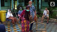 Seorang lansia berjalan saat latihan angklung di Rumah Rehabilitasi Psikososial Dinas Sosial Kota Tangerang, Banten, Rabu (19/5/2021). Kegiatan berlatih angklung bagi lansia tersebut guna mengisi waktu luang sekaligus melatih motorik, auditori, dan sensorik para lansia. (Liputan6.com/Angga Yuniar)