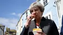 Ekspresi PM Inggris, Theresa May saat mencicipi keripik disela pemberhentinya untuk kampanye di Mevagissey, Cornwall, Selasa (2/5). Foto ini menjadi perbincangan karena Theresa May terlihat konyol saat mengemil. (AFP PHOTO/POOL/DYLAN MARTINEZ)