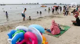 Wisatawan mengunjungi Pantai Lagoon di kawasan Ancol Taman Impian, Jakarta, Selasa (18/6/2024). (Liputan6.com/Herman Zakharia)