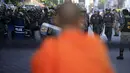 Seorang biksu Buddha memperhatikan aksi polisi memblokir jalan untuk mencegah pengunjuk rasa mendekat ke Phnom Penh Municipal Court, di pusat kota Phnom Penh, Kamboja, (30/5/2014). (REUTERS/Samrang Pring)