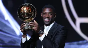 Penyerang Paris Saint-Germain (PSG), Ousmane Dembele, mengangkat trofi Ballon d'Or 2025 yang diraihnya di Theatre du Chatelet, Paris, Selasa (23/9/2025) dini hari WIB. (Franck FIFE / AFP)
