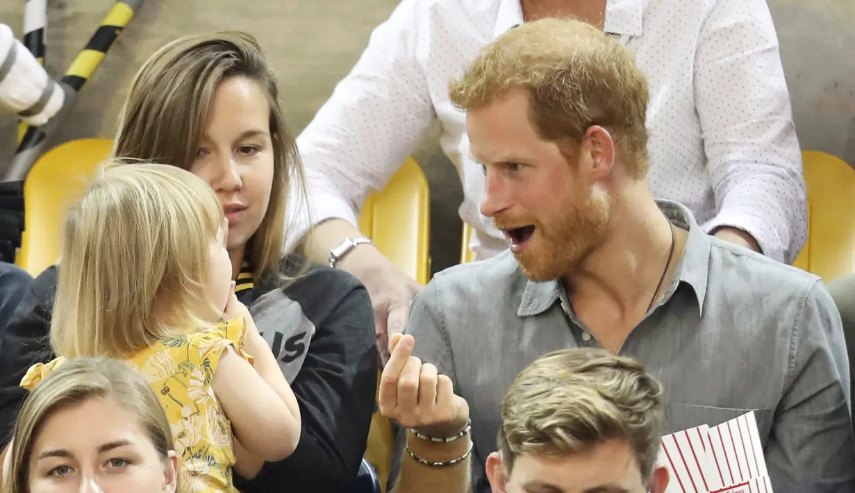 Pangeran Harry mengambilkan Emily Henson popcorn dan menyuapinya ketika acara Invictus Games 2017 di Toronto, Kanada, Rabu (27/9). Bocah itu merupakan anak atlet David Henson yang juga rekan dari Pangeran Harry. (CHRIS JACKSON/GETTY IMAGES/AFP) 