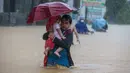 Seorang warga menggendong anaknya menembus genangan banjir yang diakibatkan oleh Topan Vamco di Provinsi Rizal, Filipina (12/11/2020). Topan Vamco membawa angin kencang dan hujan deras yang memicu tanah longsor, longsor batu, serta banjir bandang. (Xinhua/Rouelle Umali)