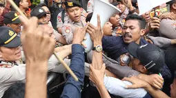 Sejumlah massa yang mengaku dari Himpunan Mahasiswa Islam terlibat aksi saling dorong dengan aparat kepolisian saat unjuk rasa di depan Gedung KPK, Jakarta, Rabu (18/9/2019). Dalam aksinya, mereka menolak pimpinan KPK terpilih periode 2019-2023. (Liputan6.com/Helmi Fithriansyah)