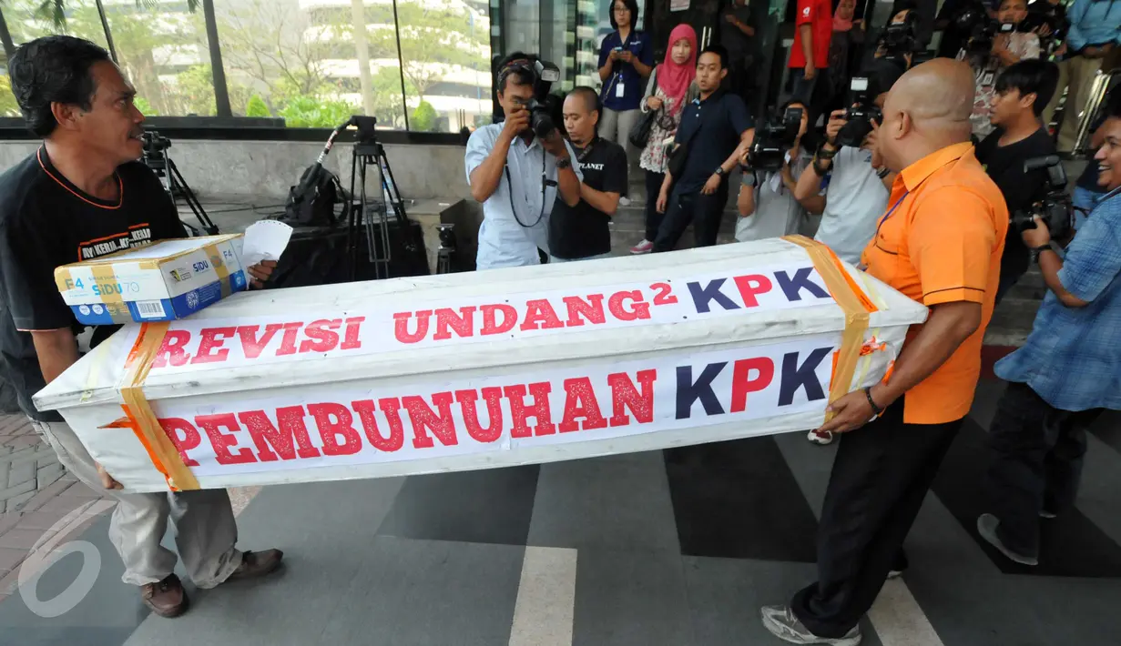 Dua orang pegawai Pos Indonesia menggotong sebuah peti mati bercat putih di Gedung KPK, Jakarta, Selasa (20/10). Peti yang bertuliskan "Revisi UU KPK, Pembunuhan KPK" itu dikirim oleh Bambang Saptono, warga Solo, Jawa Tengah. (Liputan6.com/Helmi Afandi)