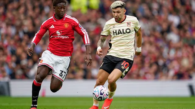 Pemain Manchester United Kobbie Mainoo (kiri) berebut bola dengan pemain Ipswich Town Julio Enciso