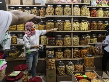 Pedagang kue kering melayani pembeli di Pasar Mayestik, Jakarta, Senin (3/5/2021). Omzet penjualan kue kering menjelang Lebaran tahun ini mengalami peningkatan hingga 70 persen dari tahun sebelumnya yang mengalami penurunan hingga 70 persen. (Liputan6.com/Johan Tallo)