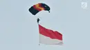 Penerjun payung membawa bendera Merah Putih saat Festival Damai Millenial Road Safety di Monas, Jakarta, Minggu (23/6/2019). Aksi puluhan penerjun payung TNI-Polri ini menjadi perhatian warga di akhir acara Festival Damai. (merdeka.com/Iqbal Nugroho)