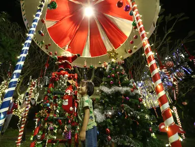 Seorang anak berpose untuk berfoto dengan dekorasi Natal di Yangon, Myanmar (10/12/2020). Berbagai dekorasi hingga akseoris dipasang untuk menyambut Natal di kota tersebut. (Xinhua/U Aung)