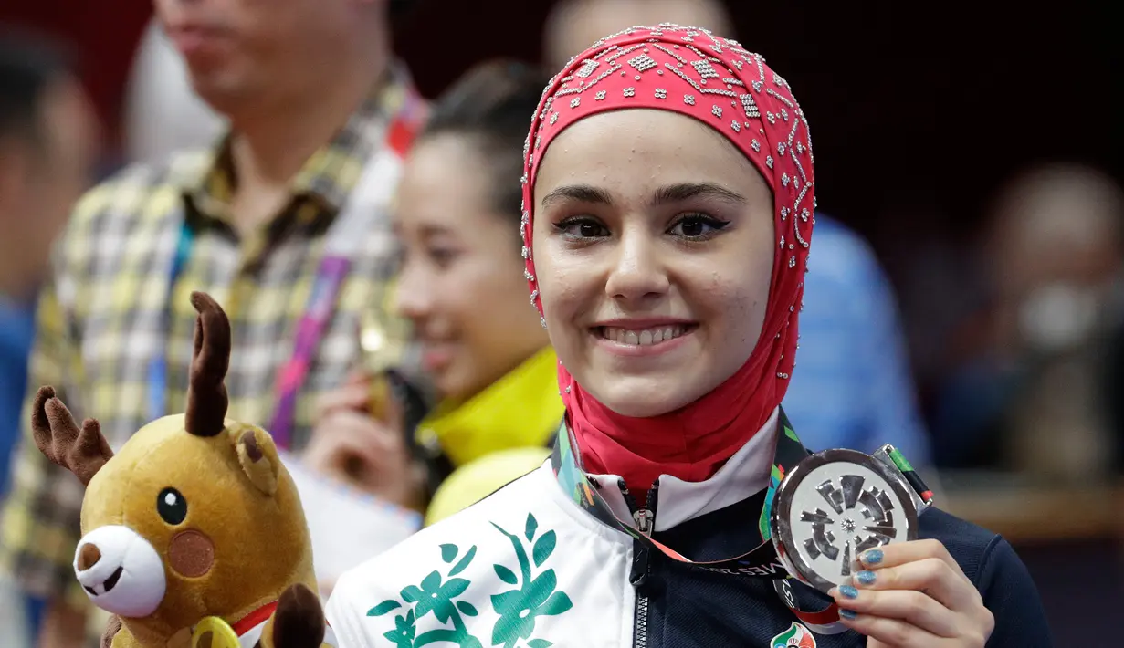 Atlet wushu Iran, Zahra Kiani menunjukkan medali perak dari nomor Qiangshu Asian Games 2018  di Jakarta, Selasa (21/8). (AP Photo/Aaron Favila)