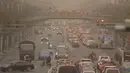 Mobil dan pejalan kaki menyusuri jalan yang diselimuti debu dan kabut di Beijing, Jumat, 10 Maret 2023. Pencakar langit menghilang ke dalam kabut dan kualitas udara anjlok saat ibu kota China diselimuti badai debu dan polusi berat. (AP Photo/Mark Schiefelbein)