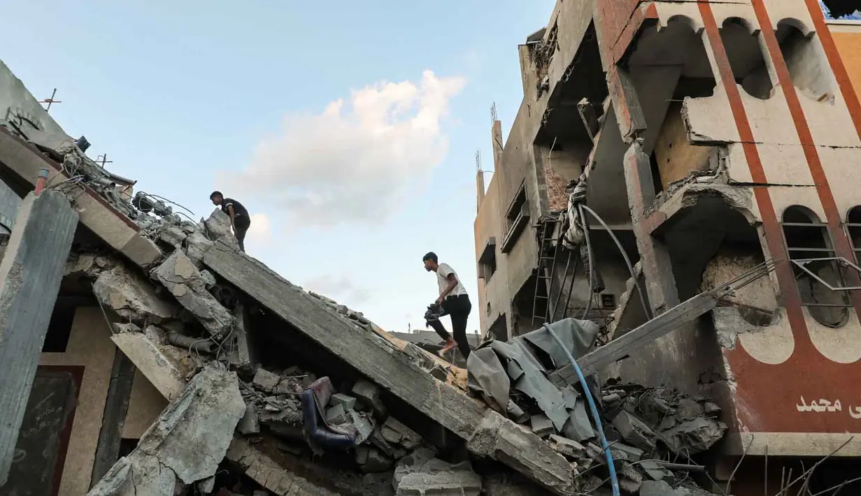 Warga Palestina memeriksa reruntuhan bangunan yang terkena serangan Israel di kamp pengungsi Nuseirat di Jalur Gaza tengah, pada 25 September 2025. (Eyad BABA/AFP)