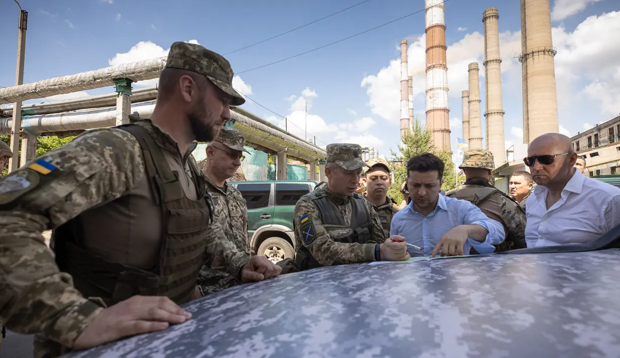 Presiden Ukraina, Volodymyr Zelensky berbincang dengan prajurit saat mengunjungi garis depan medan pertempuran dengan separatis pro-Rusia di Lugansk, Senin (27/5/2019). Zelensky berada pada jarak sekitar 400 meter dari lokasi para pemberontak. (STR/UKRAINE PRESIDENTIAL PRESS SERVICE/AFP)