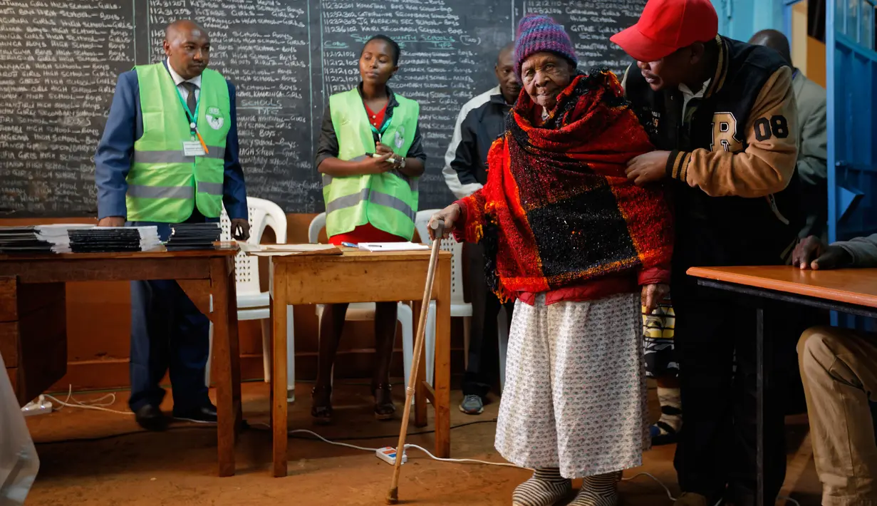 Lydia Gathoni Kiingati (102) menggunakan tongkat mendatangi sebuah TPS untuk memberikan suaranya di Gatundu, utara Nairobi, Selasa (8/8). Masyarakat Kenya melaksanakan pesta demokrasi dengan memberikan suara pada pemilihan presiden. (AP Photo/Ben Curtis)