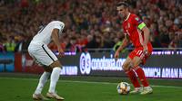 Gelandang Wales, Gareth Bale, berusaha melewati bek Azerbaijan, Pavlo Pashayev, pada laga Kualifikasi Piala Eropa 2020 di Cardiff City Stadium, Cardiff, Jumat (6/9). Wales menang 2-1 atas Azerbaijan. (AFP/Geoff Caddick)