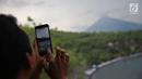 Wisatawan mengambil foto Gunung Agung dari kawasan Pantai Amed, Karangasem, Bali, Rabu (6/12). Kawasan Amed ini juga terkenal dengan lokasi wisata air. (Liputan6.com/Immanuel Antonius)