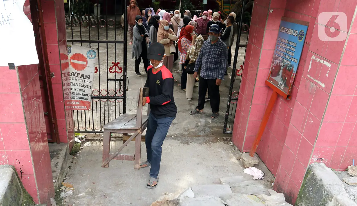 Petugas membawa bangku untuk dijadikan jalan darurat di SDN Pondok Cina 1, Depok, Jawa Barat, Rabu (9/11/2022). Pembangunan trotoar Jalan Margonda Raya yang tidak membuat jalan darurat untuk siswa tersebut menghalangi pintu masuk SDN Pondok Cina 1 serta membahayakan siswa. (Liputan6.com/Herman Zakharia)