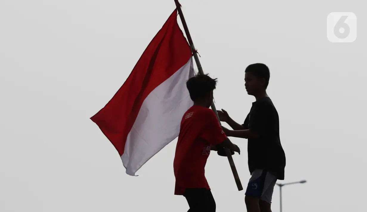 Dua orang anak mengibar-ngibarkan bendera Merah Putih usai pelaksanaan Upacara Peringatan HUT RI ke-77 di Kawasan Kalibaru Barat, Cilincing, Jakarta, Rabu (17/8/2022). Memperingati Hari Kemerdekaan Indonesia ke-77, anak-anak yang tergabung dalam Kelas Jurnalis Cilik bersama para relawan melaksanakan upacara bendera dan beragam lomba. (Liputan6.com/Helmi Fithriansyah)