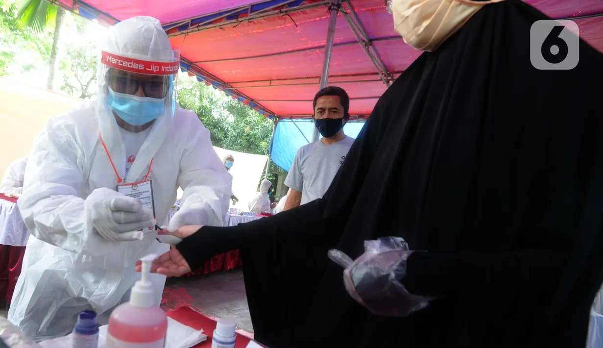 Petugas berpakaian baju hazmat menandai jari warga dengan tinta usai mencoblos dalam Pilkada Tangerang Selatan 2020 di TPS 46, Paku Jaya, Serpong Utara, Rabu (9/12/2020). Para petugas KPPS di TPS 46 ini mengunakan seragam APD untuk mengantisipasi penyebaran COVID-19. (merdeka.com/Arie Basuki)
