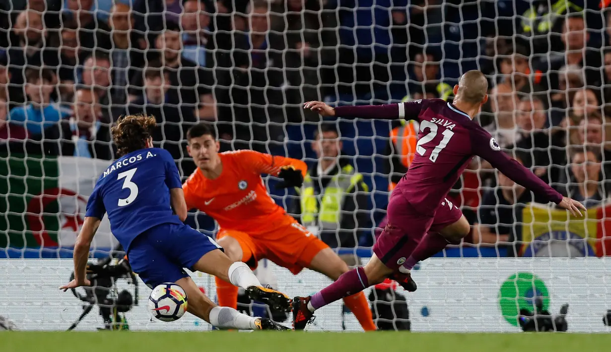 Pemain Manchester City, David Silva melakukan tendangan yang berhasil diblok oleh pemain Chelsea Marcos Alonso saat pertandingan Liga Inggris di Stamford Bridge, London (30/9). (AP Photo/Kirsty Wigglesworth)
