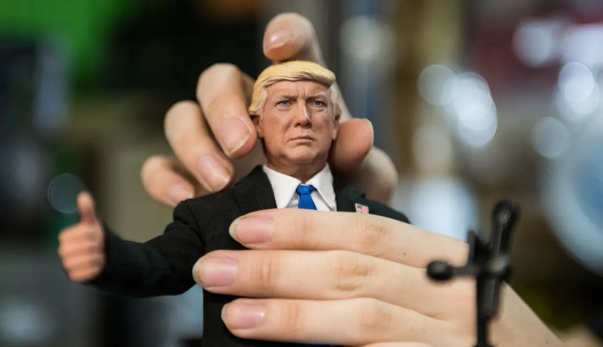 Pekerja membetulkan kepala boneka Presiden AS Donald Trump saat pidato di toko mainan, Hong Kong (3/2). (AFP Photo/Anthony Wallace)
