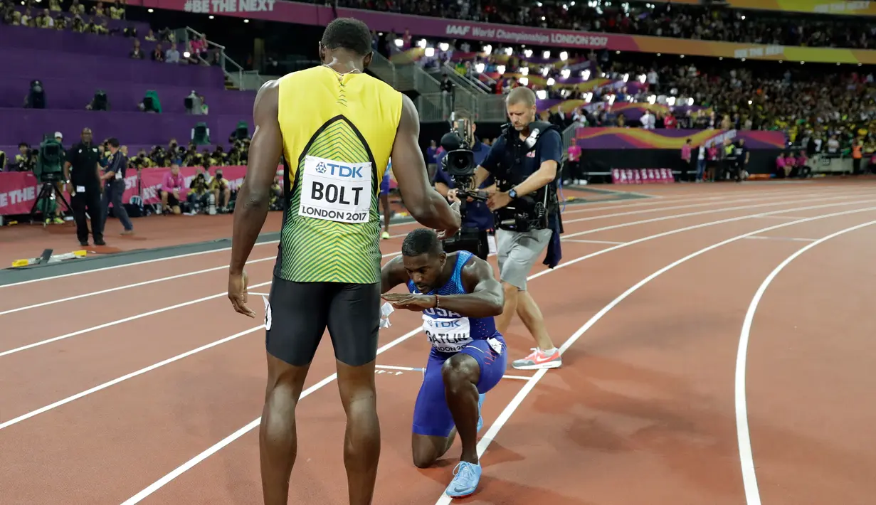 Pelari AS, Justin Gatlin berlutut di hadapan Usain Bolt usai menjadi juara pada lomba lari 100 meter Kejuaraan Dunia Atletik 2017 di Stadion London, Minggu (6/8). Gatlin menjadi pelari tercepat dengan catatan waktu 9.92 detik. (AP/Matthias Schrader)