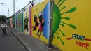 Seorang pria mengendarai sepeda melewati mural kesadaran virus corona COVID-19 di sepanjang pinggir jalan di Chennai, India, 13 September 2021. India bersiap hadapi kemungkinan lonjakan kasus COVID-19 sekitar musim festival September hingga November. (ARUN SANKAR/AFP)