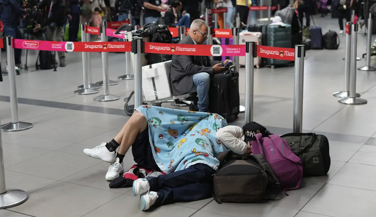 Seorang penumpang maskapai Viva Air tidur di bandara setelah maskapai berbiaya rendah itu menangguhkan operasinya di Bandara Internasional El Dorado di Bogota, Kolombia, Selasa (28/2/2023). Sejumlah penumpang bermalam di bandara, banyak yang tidur di lantai sambil menunggu penerbangan ke tujuan yang dituju. (AP Photo/Fernando Vergara)