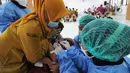 Petugas kesehatan menyuntikkan vaksin COVID-19 kepada siswa di SDN 02 Ciater, Tangerang Selatan, Selasa (14/12/2021). Mulai Hari ini, 11 provinsi di Indonesia secara serentak melaksanakan vaksinasi COVID-19 dengan sasaran anak berusia 6 hingga 11 tahun. (merdeka.com/Arie Basuki)