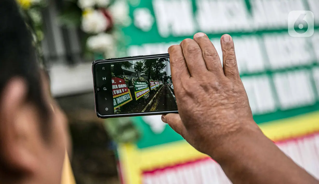 Warga mengambil foto karangan bunga di depan Gedung Kejaksaan Agung RI, Jakarta, Selasa (27/10/2020). Karangan bunga berasal dari korban terdampak kasus asuransi Jiwasraya yang mengharapkan kasus mega skandal itu bisa segera tuntas dan memberikan keadilan bagi mereka. (Liputan6.com/Faizal Fanani)