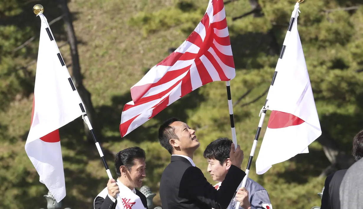 Simpatisan mengibarkan bendera nasional Jepang di dekat Istana Kekaisaran untuk merayakan ulang tahun ke-60 Kaisar Naruhito di Tokyo, Minggu, (23/2/2020). Kaisar Jepang Naruhito menandai ulang tahun dengan simpatinya kepada mereka yang terkena virus COVID-19. (AP Photo/Koji Sasahara)